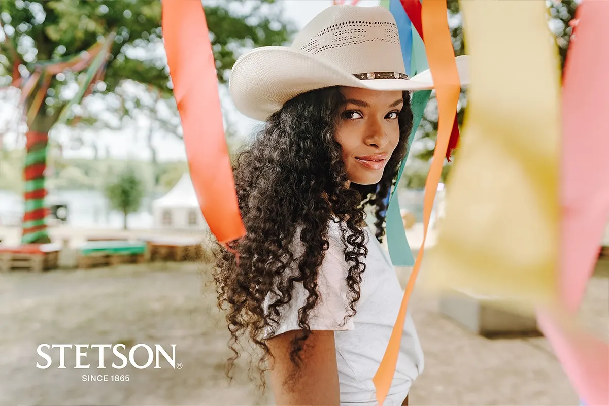Damenhüte von Stetson – Western-Flair trifft auf Design | Rockhats Frau mit weißem Westernhut von Stetson auf einem Festival, farbige Bänder im Vordergrund
